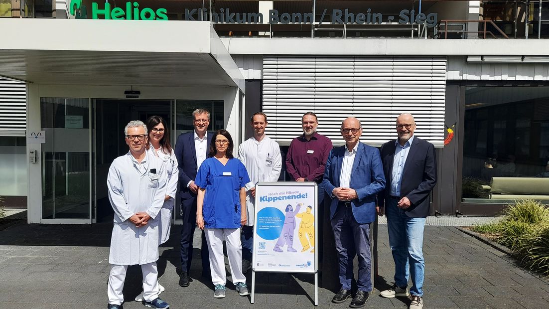 Gruppenfoto: Burkhard Blienert, Sucht- und Drogenbeauftragter der Bundesregierung, mit weiteren Personen vor einem Krankenhaus